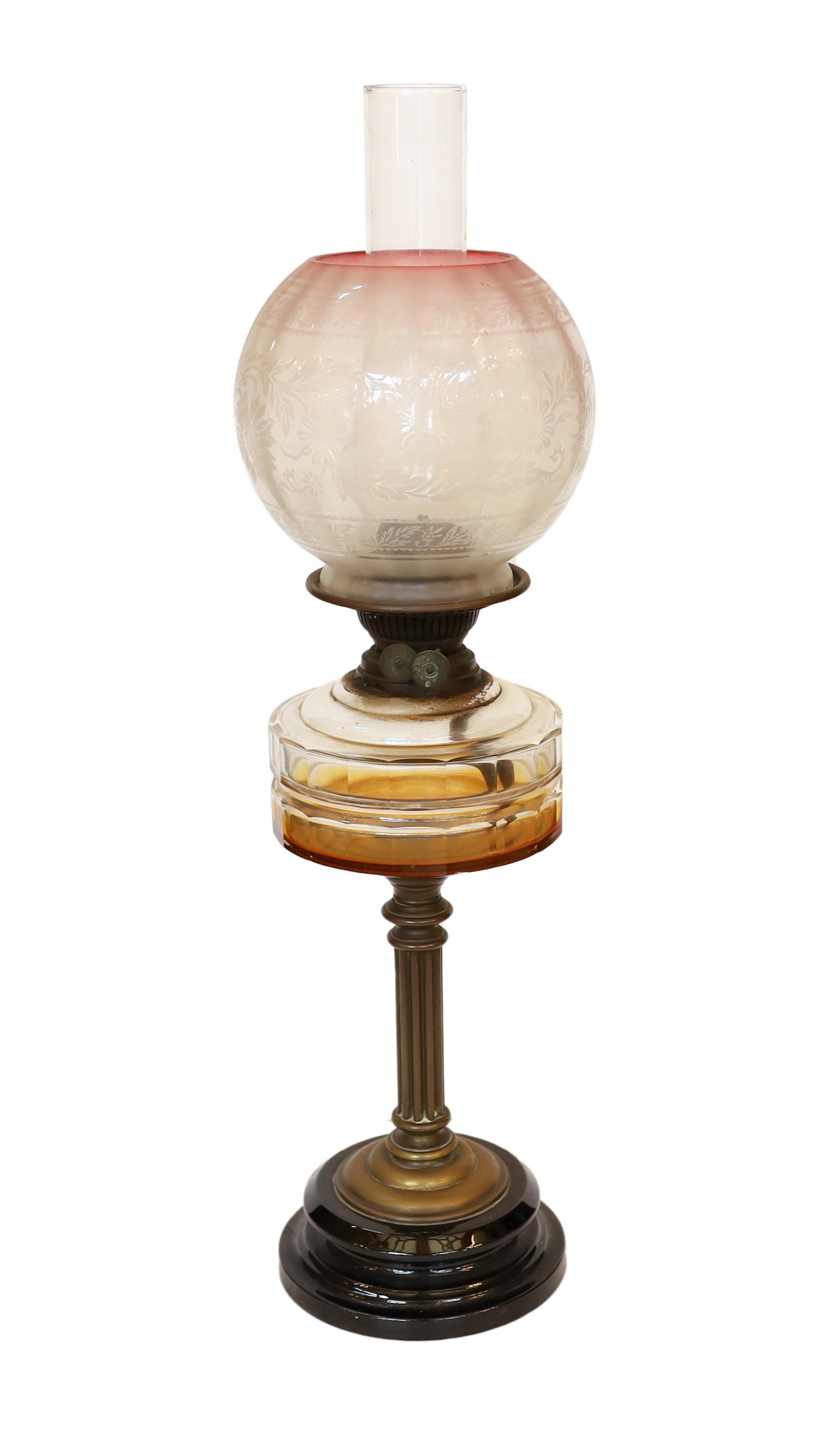 An Edwardian brass oil lamp with cut glass reservoir and pink tinted etched glass globe and flue, height overall 65cm